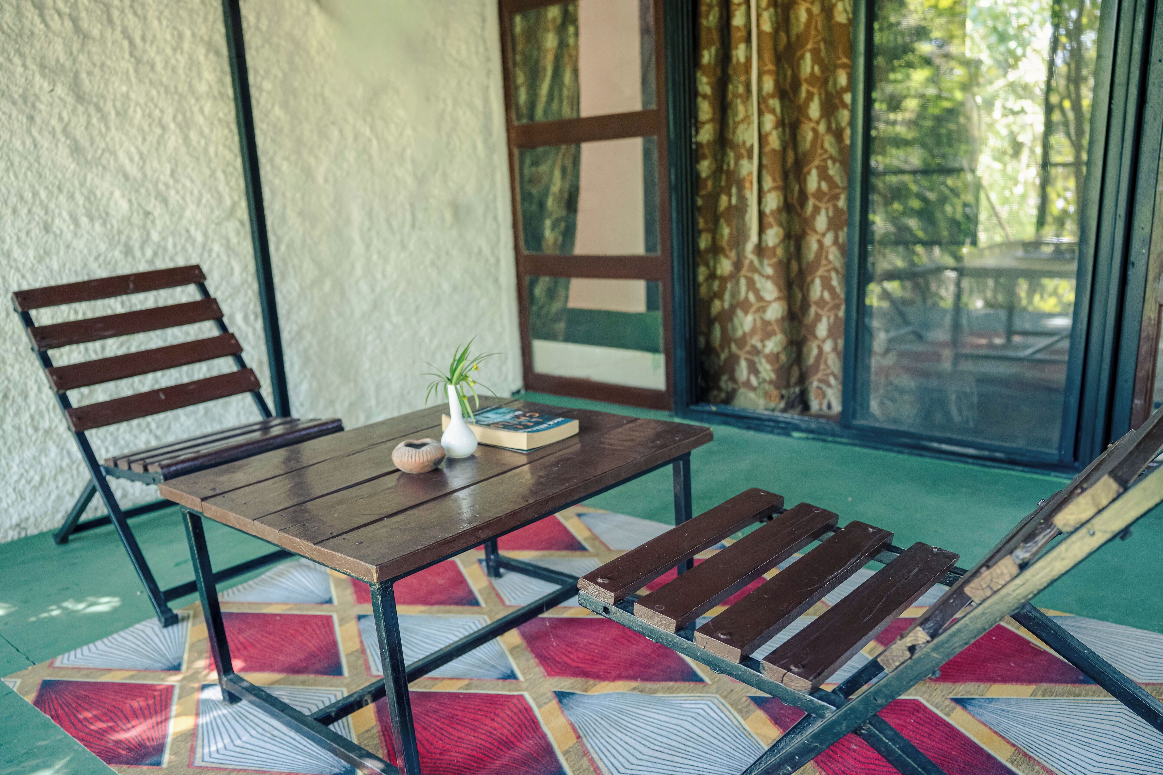A wooden table with a book and a small vase, a wooden bench, and a colorful geometric rug.