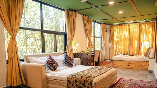 A bedroom with a large bed, a smaller bed, a desk, and a chair. - Wilderness camp Resort Pench (Kurai)