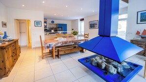 A modern kitchen with a central island, a dining table, and a blue gas stove. - Large, bright renovated farmhouse (Étel)