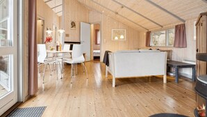 A cozy cabin interior with a dining area, sofa, and fireplace.