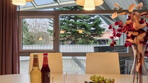 A table with bottles, a glass, and a bowl of fruit.