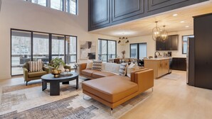 A spacious living area with a large sectional sofa, a coffee table, and a dining area with a kitchen in the background. - Indoor Pool, Hot Tub, Firepit, Theater | All-Season Retreat | Kings Crown (Gatlinburg)