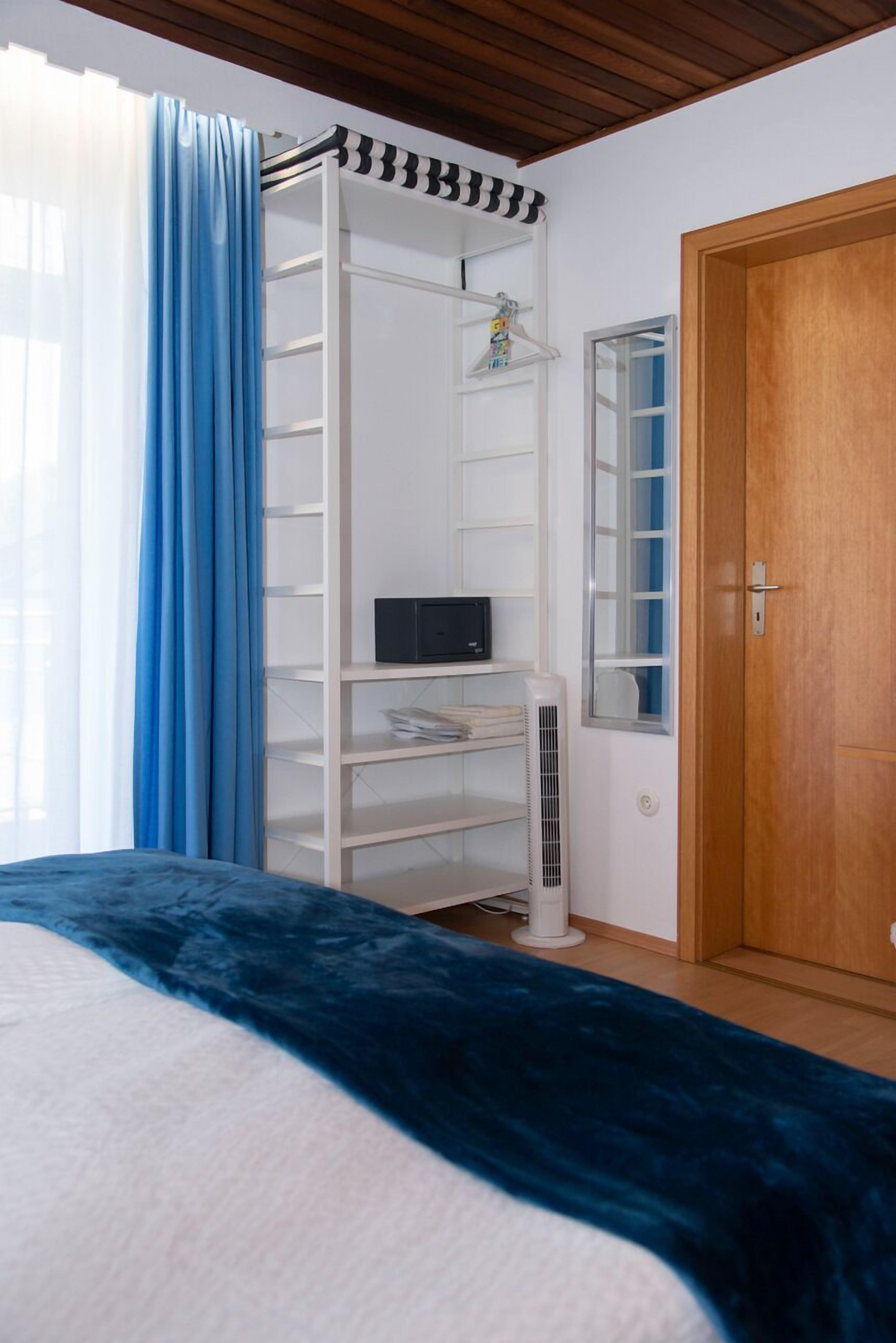 Une chambre à coucher avec un lit, une étagère blanche, un miroir et une porte.