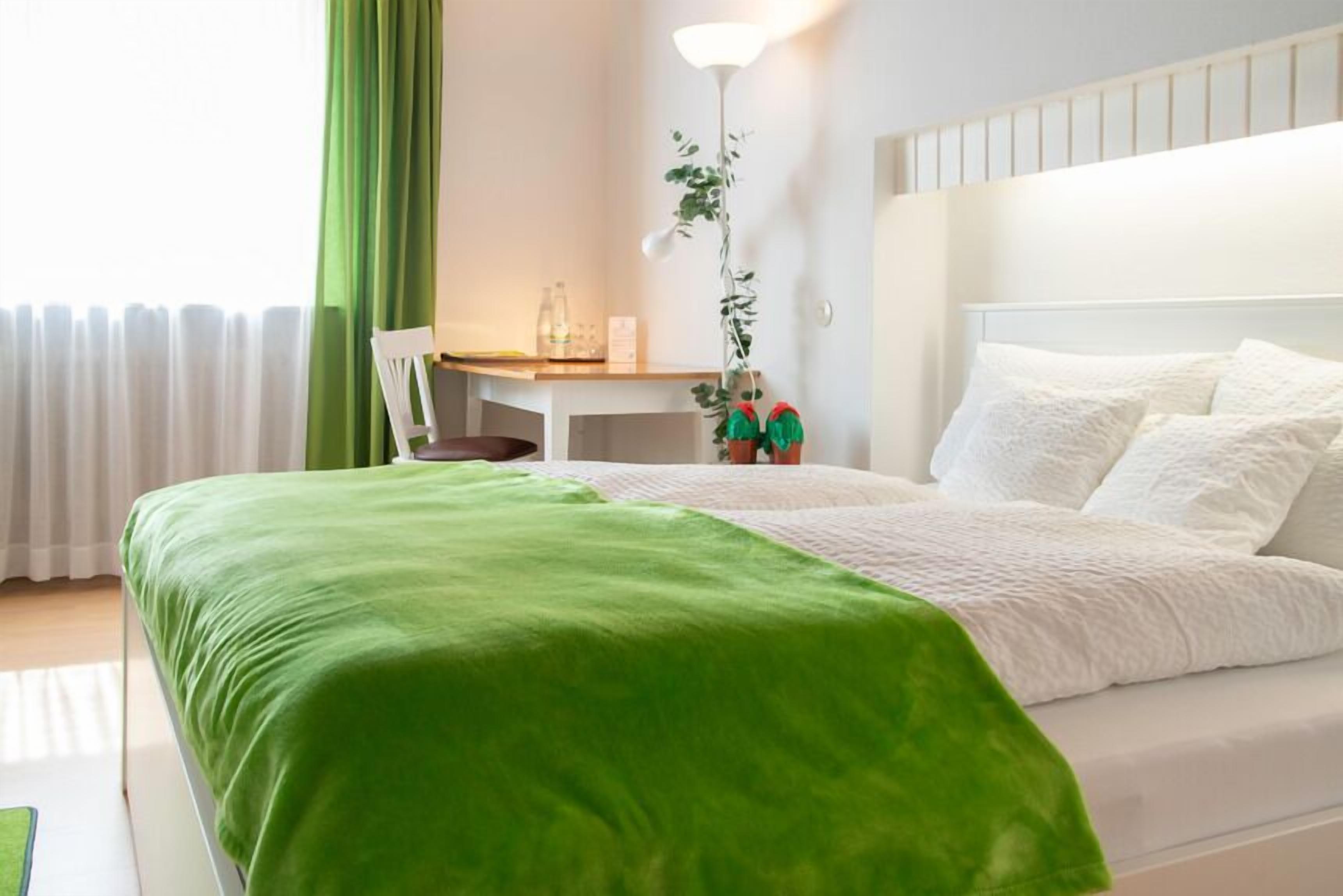 A neatly arranged hotel room with a bed, a desk, and a chair.
