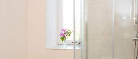 A modern bathroom with a glass shower enclosure, a white sink, and a towel rack.