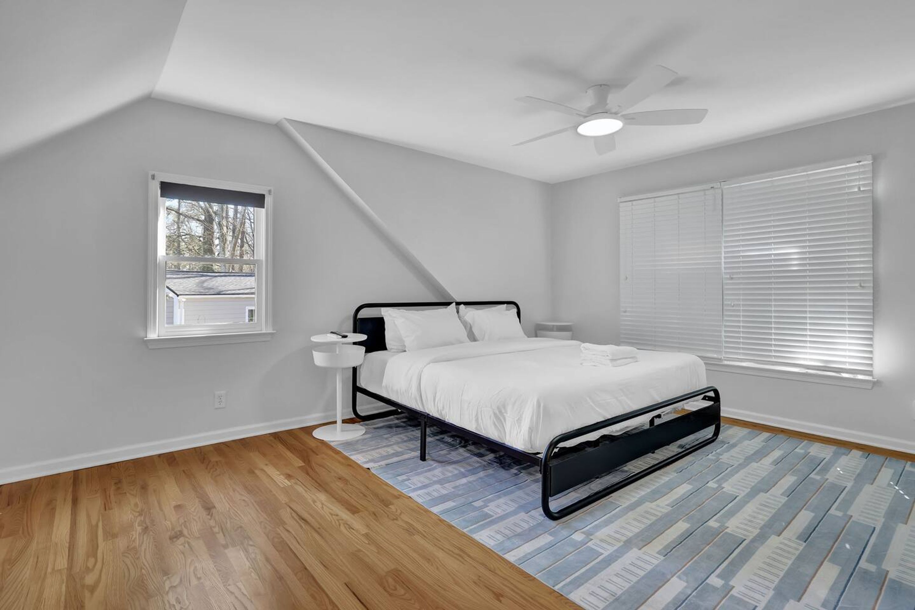 Une chambre à coucher avec un lit, un ventilateur de plafond, une fenêtre et une vue sur l’extérieur.