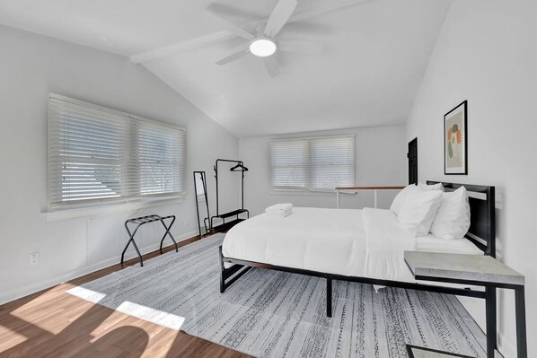 A bedroom with a bed, a bedside table, a ceiling fan, and a window with blinds. - Chamblee Retreat 3BR Home w Spacious Porch (Chamblee)