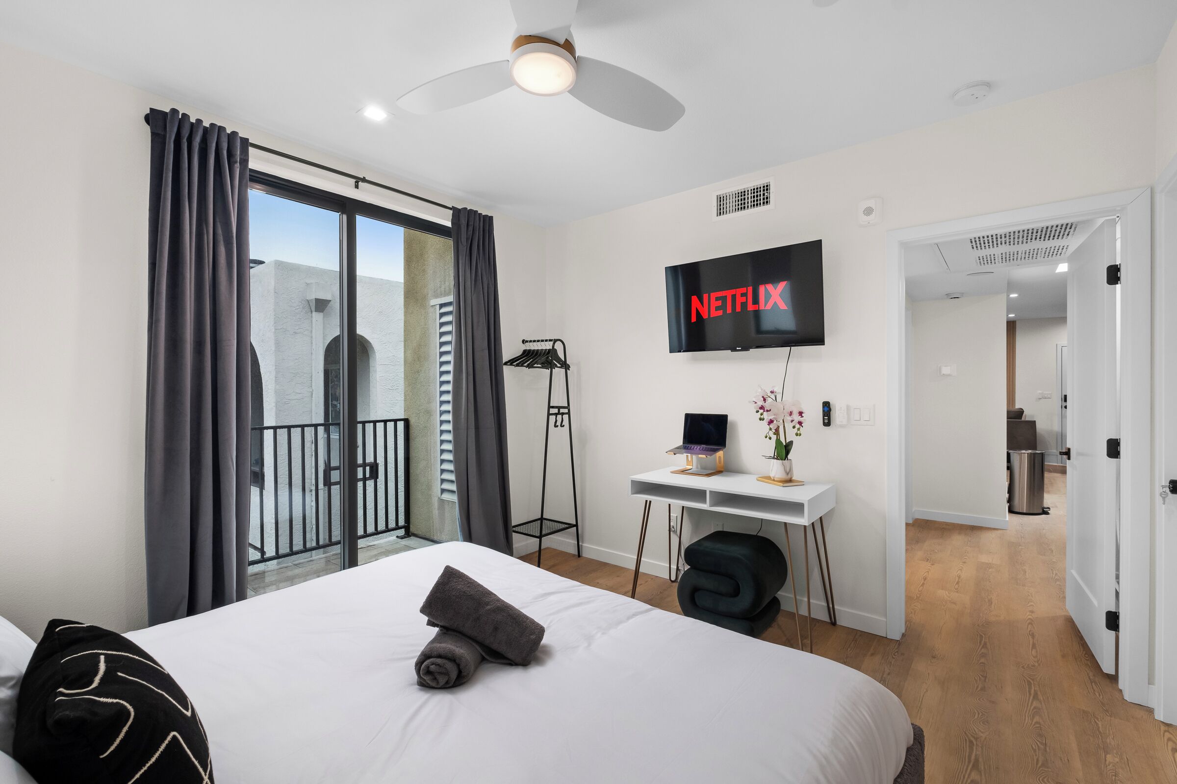 A modern hotel room with a bed, a desk, and a TV mounted on the wall.