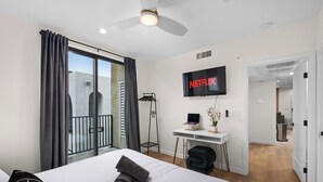 Ein modernes Hotelzimmer mit einem Bett, einem Schreibtisch und einem an der Wand befestigten Fernseher.