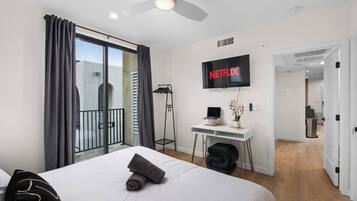 Une chambre d’hôtel moderne équipée d’un lit, d’un bureau et d’un téléviseur fixé au mur.
