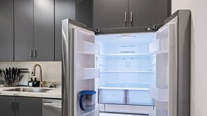 Ein offener Kühlschrank mit Wasserspender und einer blauen Kanne im Inneren.