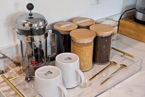 A kitchen counter with a coffee maker, jars, and utensils. - King Bed, EV Charger, Sleeps 8, Balcony, Laundry (San Diego)
