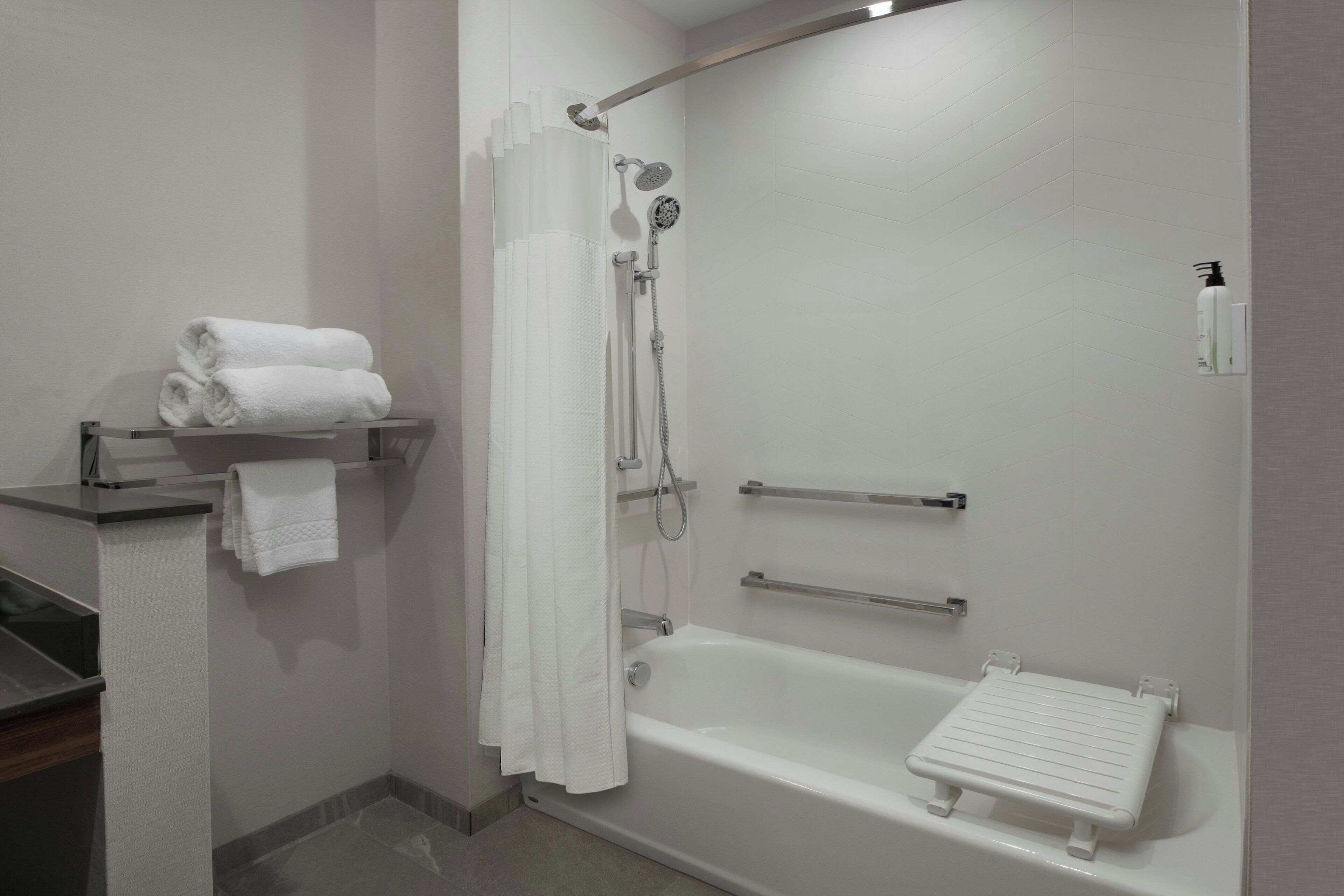 Un baño moderno con bañera, ducha y un perchero con toallas dobladas.