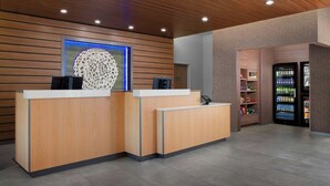 A reception area with wooden reception desks, a blue-lit wall decoration, and a vending machine.
