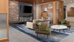 A modern living room with a stone accent wall, a flat-screen TV, a dining area, and a cozy seating arrangement.