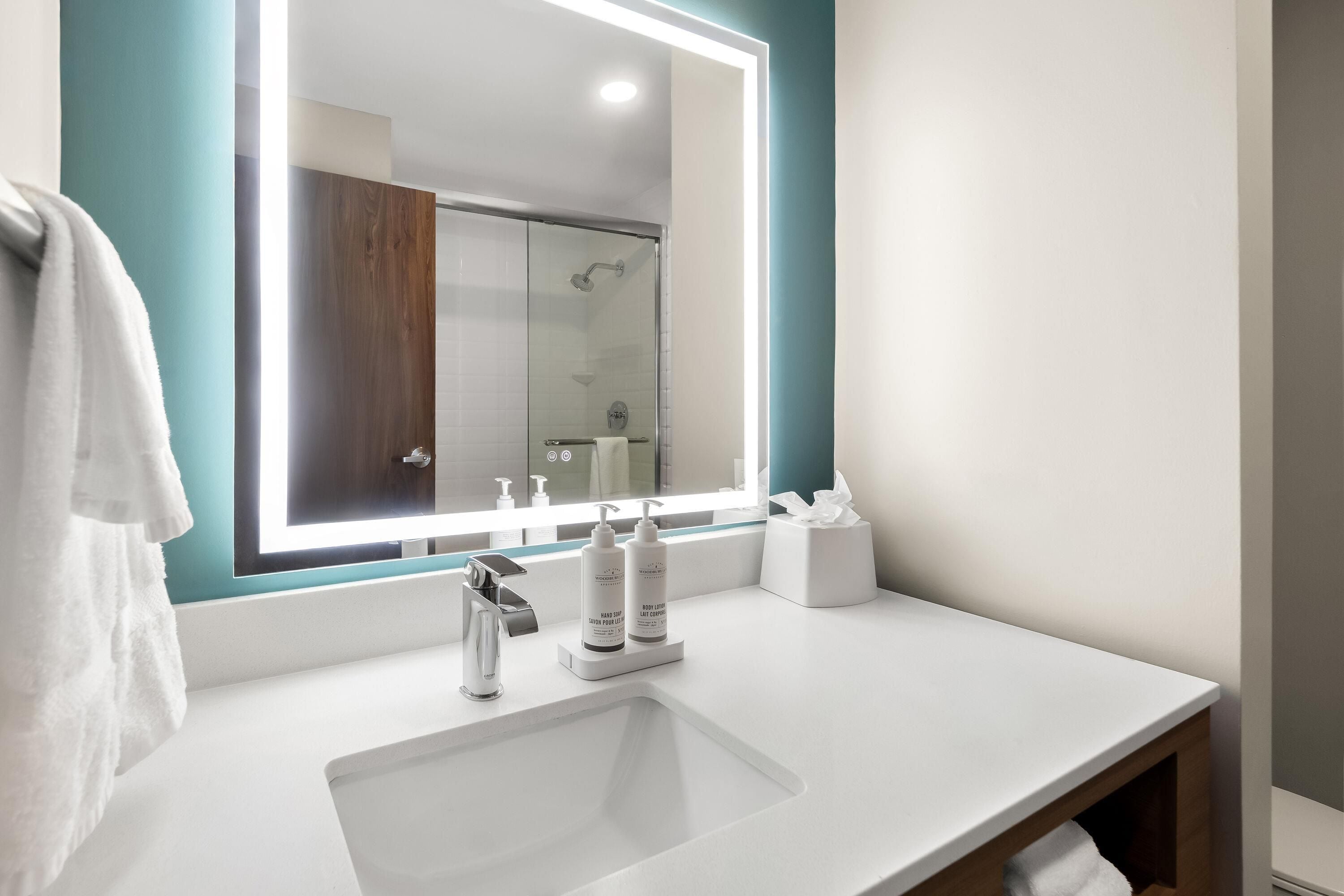 A modern bathroom with a large mirror, a white sink, and a glass shower enclosure.