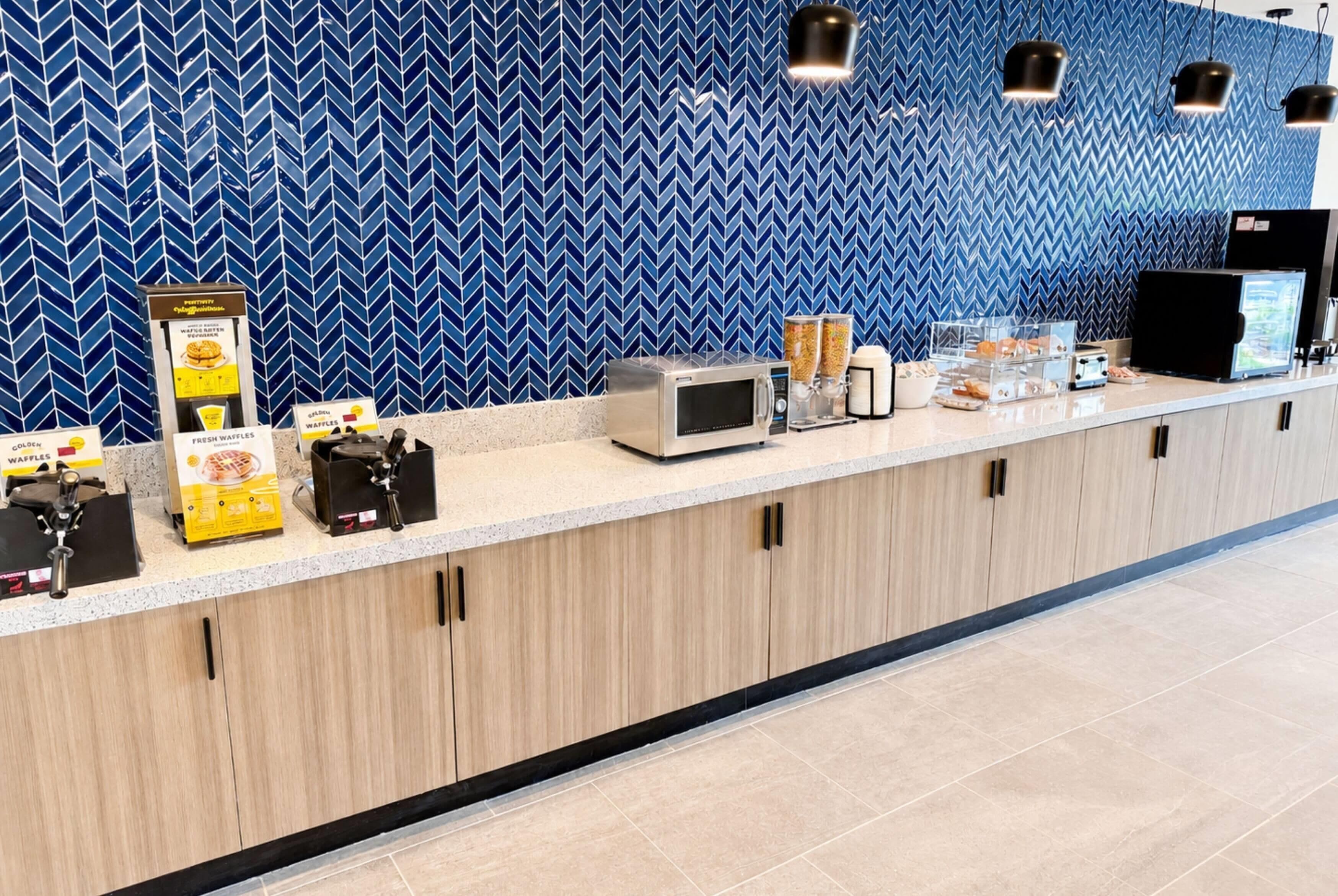 Een aanrecht met apparatuur voor het maken van wafels, een magnetron en een koffieapparaat.