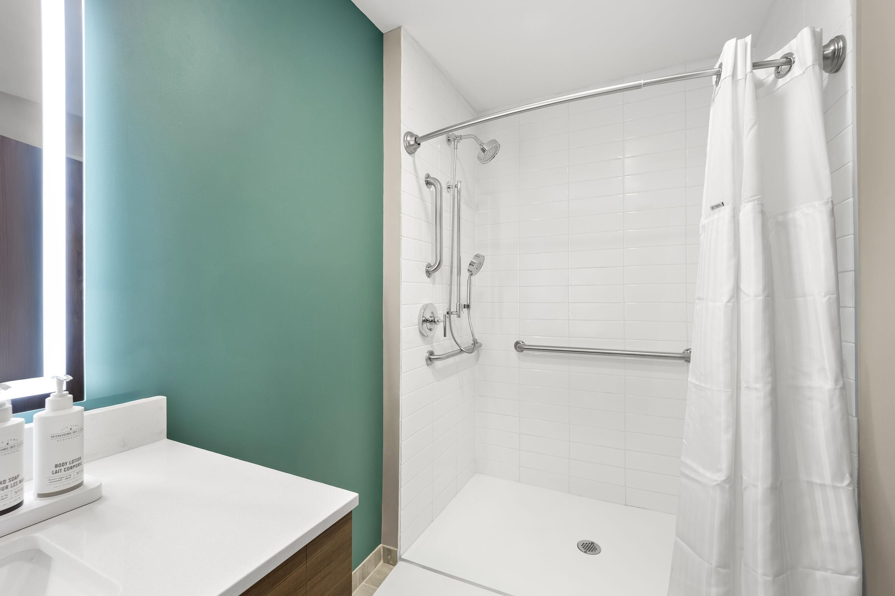 Un baño con ducha, un lavamanos blanco y un espejo.