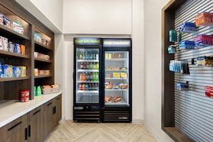 Máquina expendedora llena de refrigerios y bebidas, junto a un estante con productos envasados.