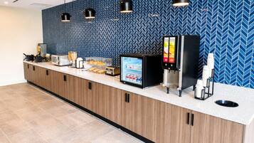 A hotel reception area with a counter, a digital menu display, a coffee machine, and a refrigerator.