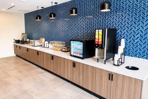 A hotel reception area with a counter, a digital menu display, a coffee machine, and a refrigerator. - La Quinta Inn & Suites by Wyndham Mebane (Mebane)