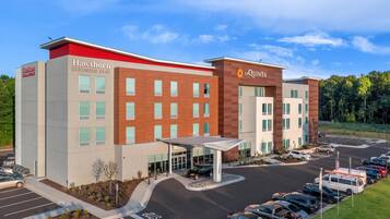 A hotel with a modern design, featuring a covered entrance and a parking lot with multiple vehicles.