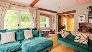 A cozy living room with a green sofa set, wooden flooring, and a fireplace. - Stone Cottage Norfolk , Lovely Family Cottage (Norwich)