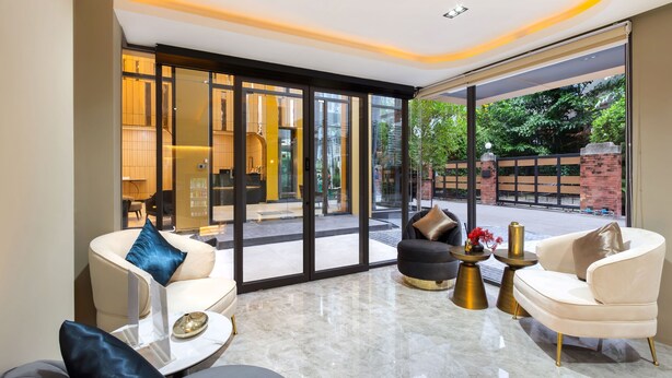 Un intérieur moderne avec une porte vitrée donnant sur un espace extérieur, comprenant un coin salon avec une table basse et une table d’appoint agrémentée d’un vase.