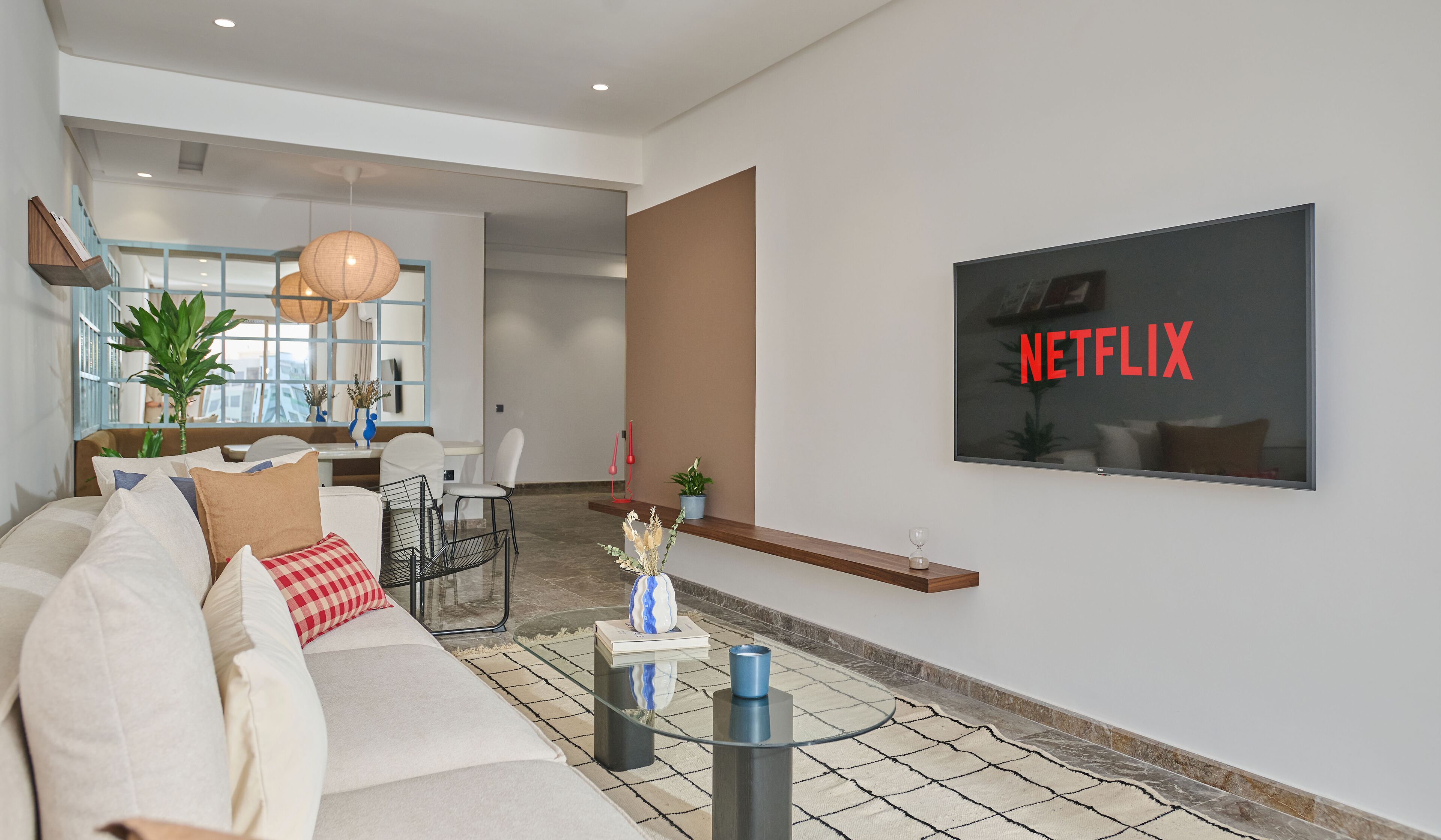 A modern living room with a sofa, coffee table, and a wall-mounted TV displaying 'NETFLIX'.