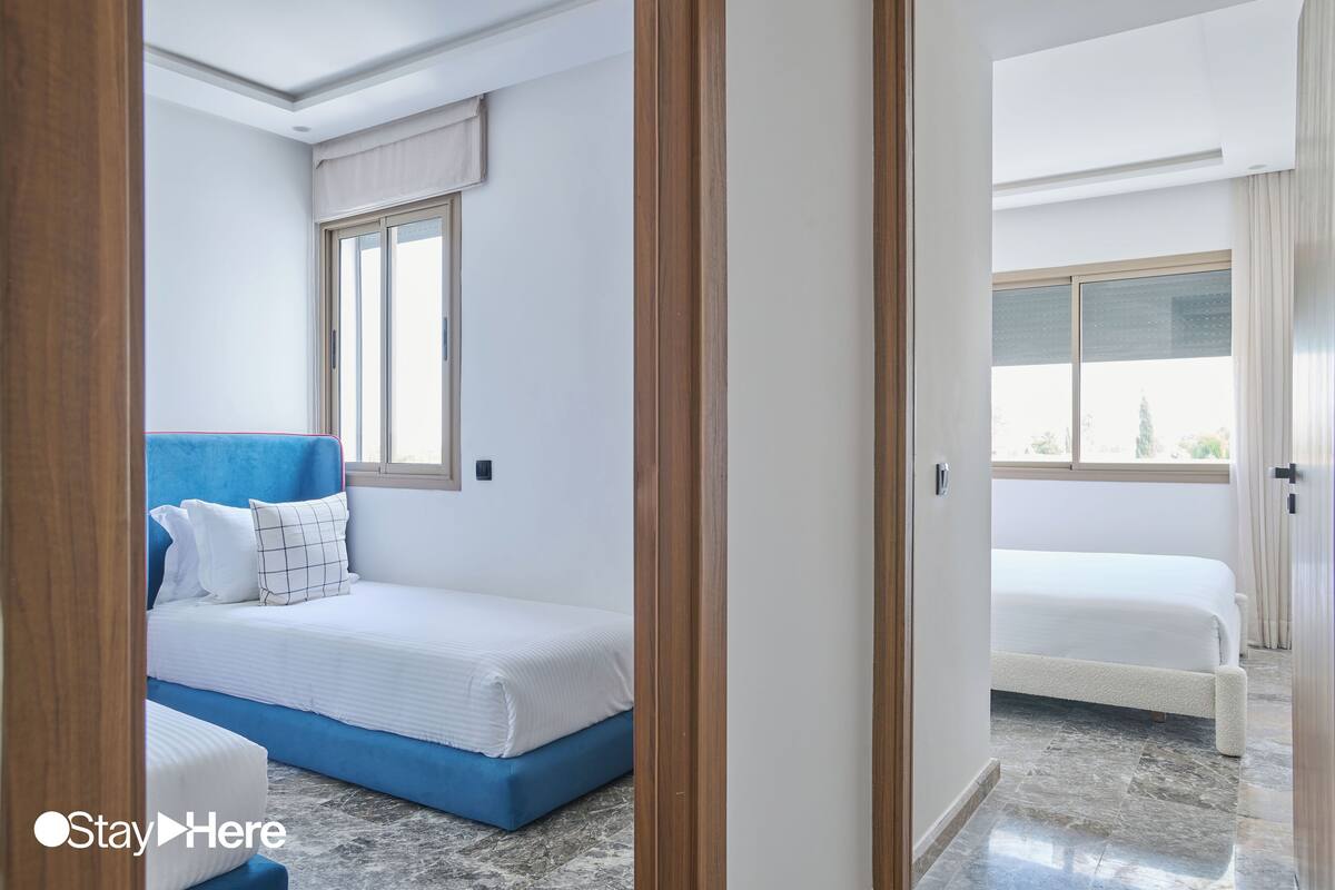 Habitación de hotel con una cama grande, una cama más pequeña y una ventana con cortinas.