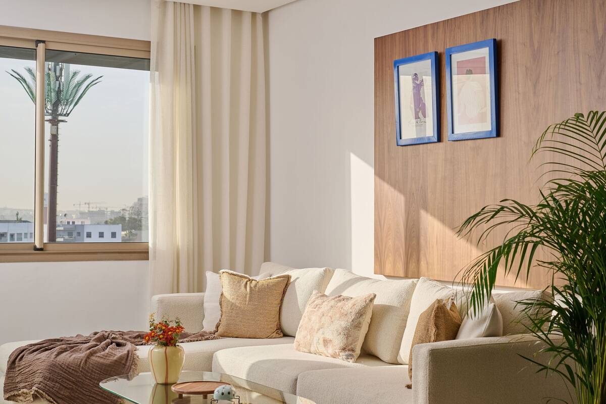 Una sala de estar moderna con un sofá, una mesa de centro, una planta en maceta y dos cuadros en la pared.