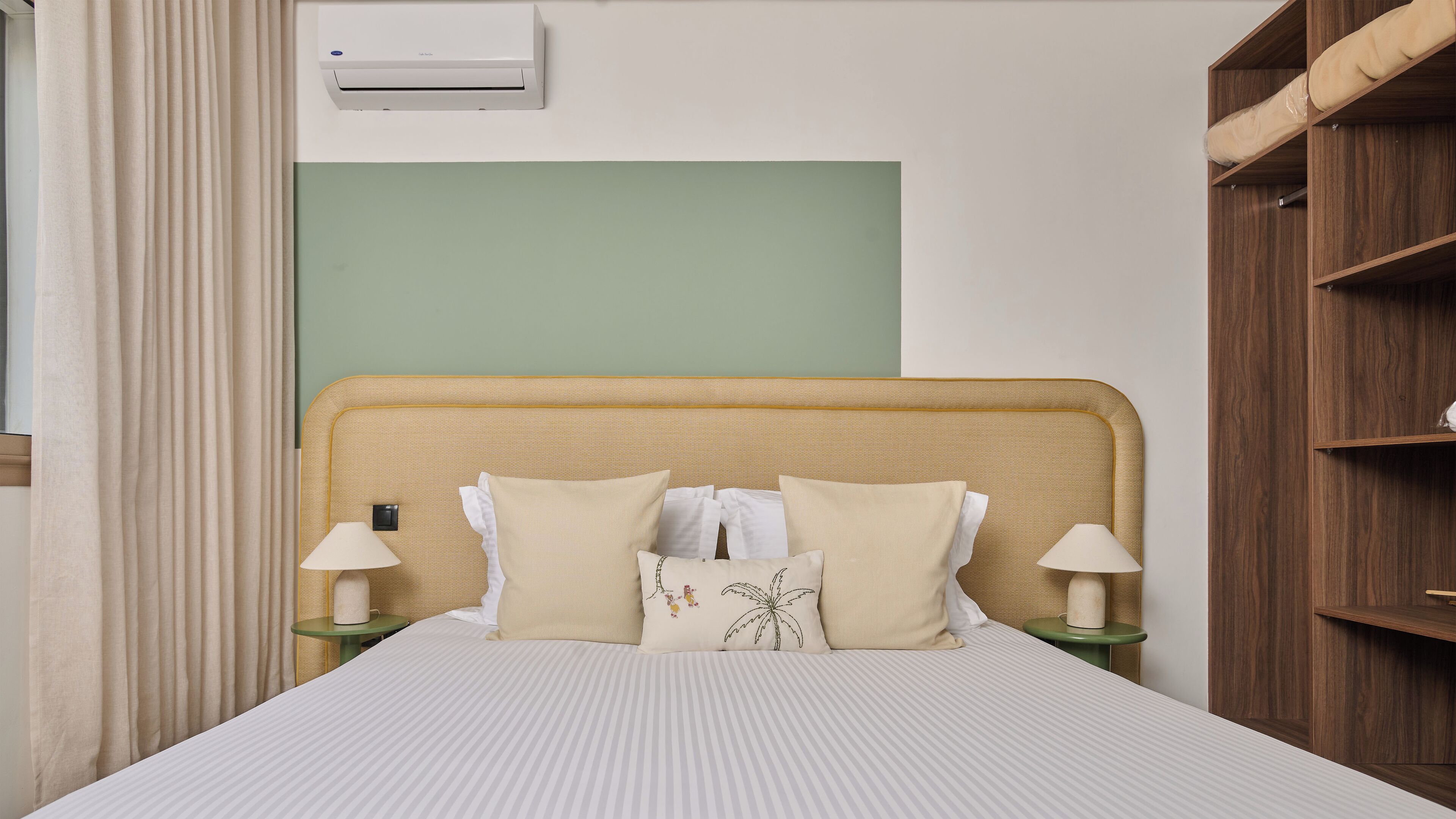 A neatly made bed with a striped bedspread, two bedside lamps, and a headboard with a simple design.