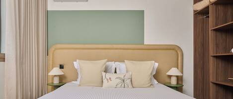A neatly made bed with a striped bedspread, two bedside lamps, and a headboard with a simple design.