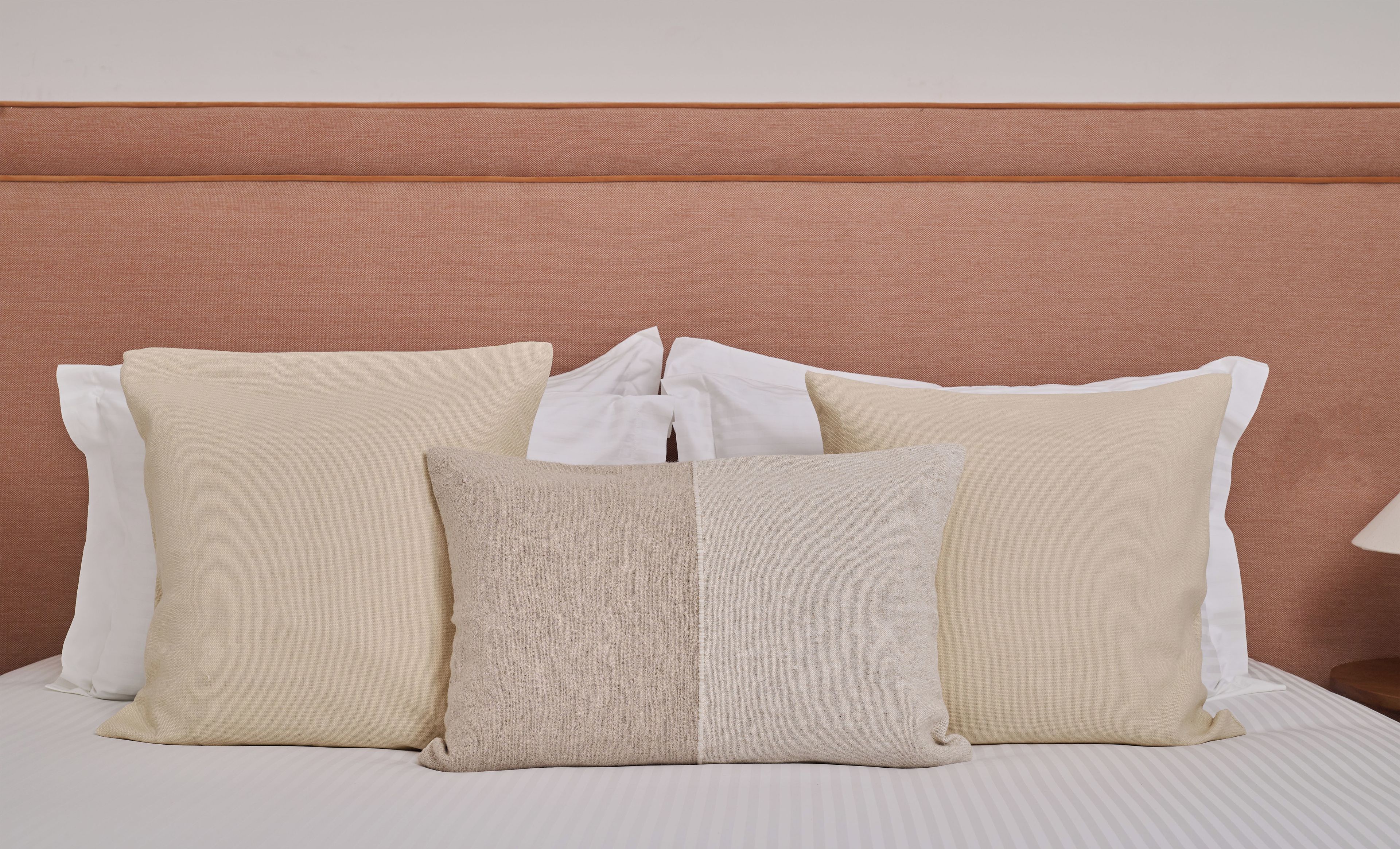 A neatly made bed with a striped white bedspread and a brown headboard.