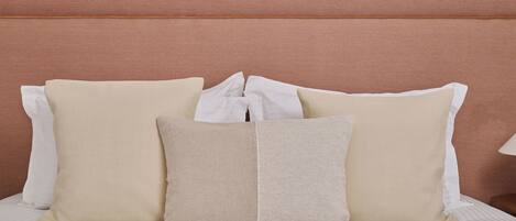 A neatly made bed with a striped white bedspread and a brown headboard.
