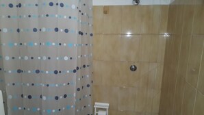 Une salle de bain avec une douche, des toilettes et un porte-serviettes.