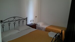 Une chambre avec un grand lit, un plus petit lit, une table de chevet avec une lampe et une chaise.
