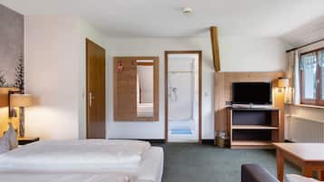 Une chambre d’hôtel avec un lit, une télévision, une douche et un bureau.