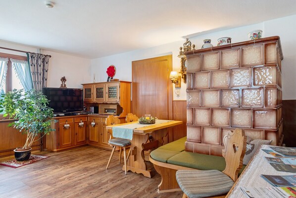 A wooden dining table with chairs, a television, and a bookshelf with decorative items.