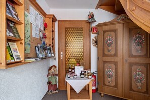 A room with a wooden cabinet, a table with jars, a corkboard with papers, and a doll.