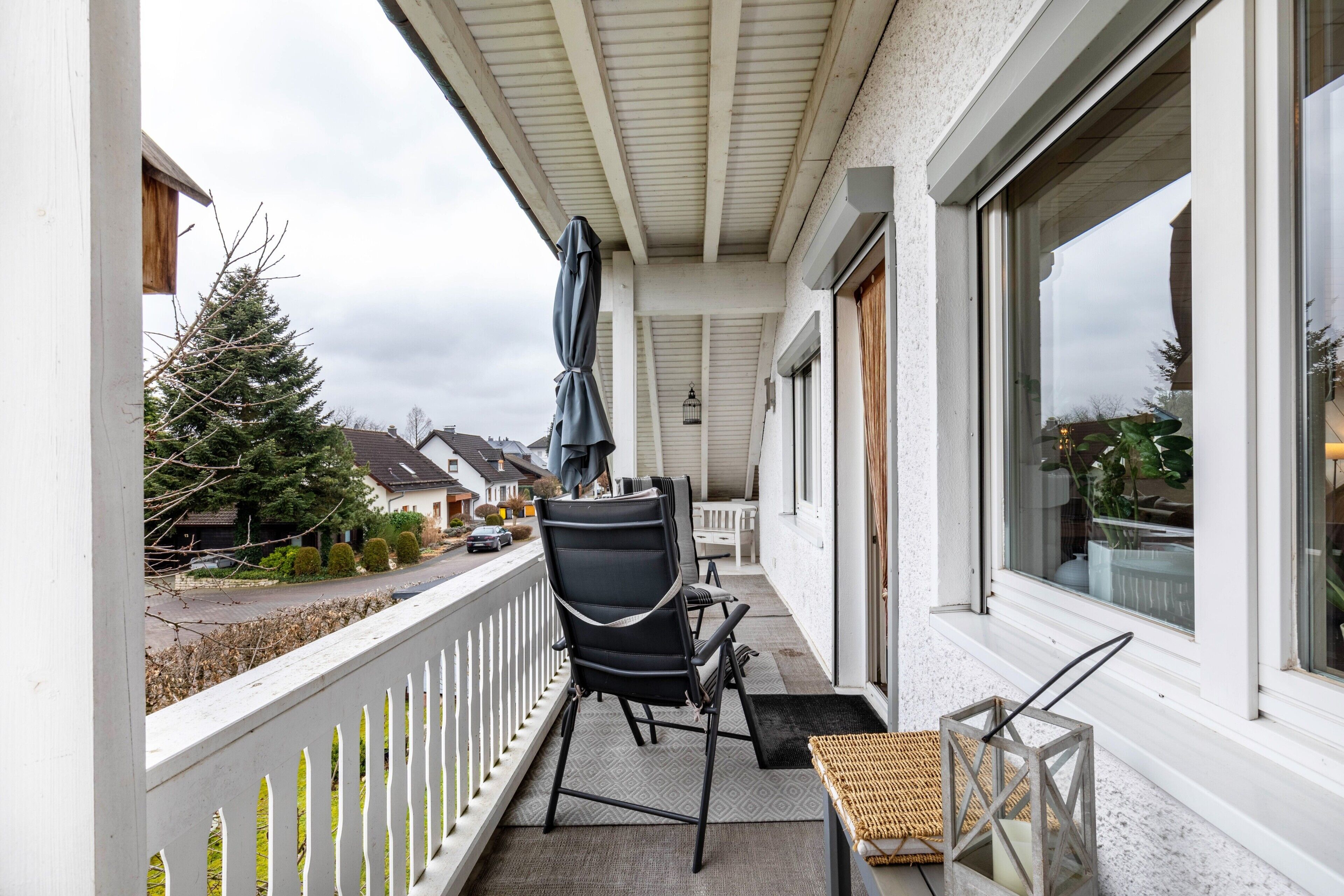 A balcony with a chair, a small table, and a lantern.