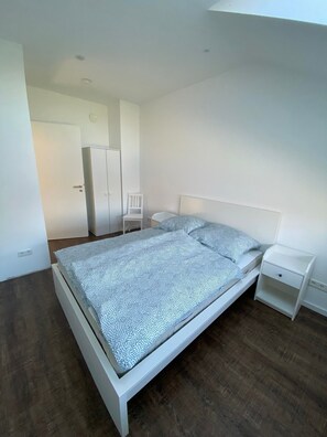 Un dormitorio con cama, mesita de noche, silla y armario.