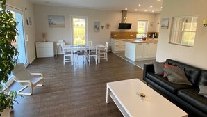 A spacious living area with a dining table, a black sofa, and a white coffee table. - Apartment 'Repetal' with Private Terrace, Garden and Wi-Fi (Attendorn)