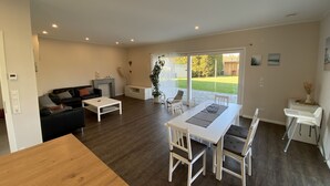 A spacious living area with a dining table, chairs, a sofa, and a fireplace. - Apartment 'Repetal' with Private Terrace, Garden and Wi-Fi (Attendorn)