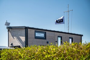 A modern building with a flag, a satellite dish, and a window.