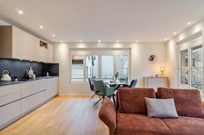 A modern kitchen with a dining area, a sofa, and a window with a view.