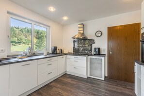 A modern kitchen with white cabinetry, a large window, and a view of greenery outside. - Apartment 'Rasche' with Balcony (Schmallenberg)