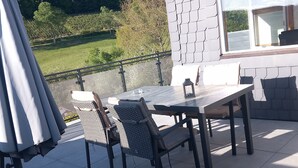 An outdoor patio with a table and chairs, a lantern, and a view of a green landscape. - Apartment 'Rasche' with Balcony (Schmallenberg)
