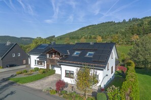 A modern house with a sloped roof, solar panels, and a well-maintained garden. - Apartment 'Rasche' with Balcony (Schmallenberg)