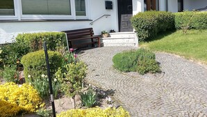 A house with a paved driveway, a bench, and a variety of flowers. - Apartment 'Rasche' with Balcony (Schmallenberg)
